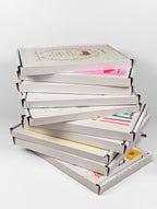 Stack of Cake Cards boxes featuring various celebration greeting card designs.